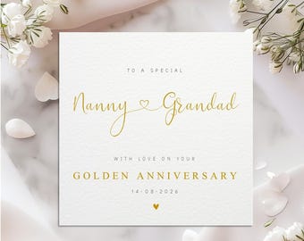 May include: A white greeting card with gold script that reads "Nanny & Grandad" and "Golden Anniversary". The card is decorated with white flowers and petals. The date "14-08-2026" is printed on the card.