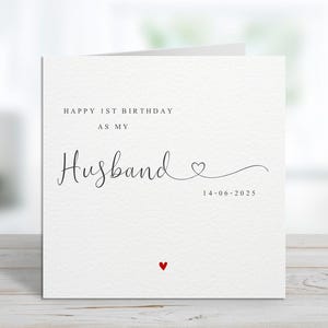 Może przedstawiać: Biała kartka z napisem "HAPPY 1ST BIRTHDAY AS MY Husband" czcionką w kolorze czarnym. Małe czerwone serce na dole i data "14-06-2025" pod słowem "Husband".