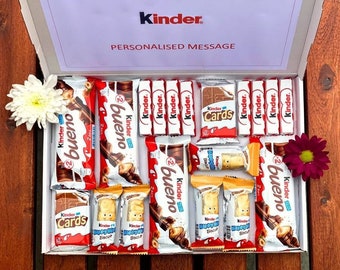 May include: A white box filled with various Kinder chocolate bars and treats, including Bueno, Cards, and Happy Hippo biscuits. The box is decorated with flowers and the text "PERSONALISED MESSAGE" and "Kinder."