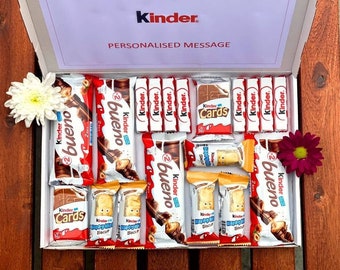May include: A white gift box filled with assorted Kinder chocolate bars, including Kinder Bueno, Kinder Chocolate, and Kinder Cards. The box has a red and white label that says "Personalized Message" and the Kinder logo.