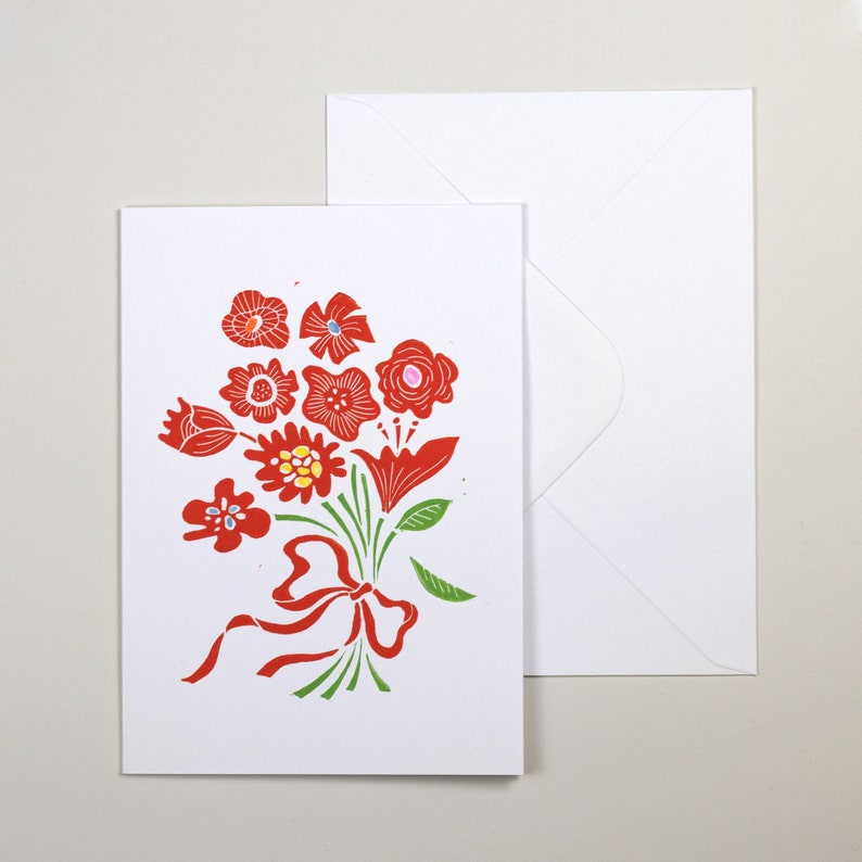 May include: A white card with a red and green floral bouquet illustration. The bouquet is tied with a red ribbon. The card is blank and comes with a white envelope.