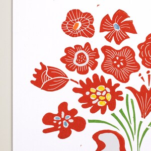 May include: A red and green floral print with a white background. The flowers are stylized and have a folk art feel. The print is perfect for a variety of projects, including fabric, paper, and home decor.