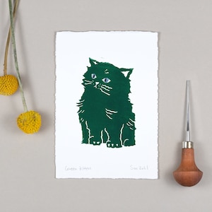 May include: A green linocut print of a cat with blue eyes. The print is titled "Green Kitten" and signed "Soo 2021".