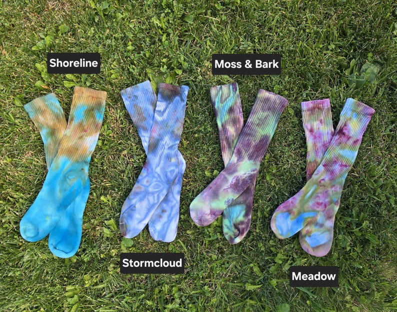 Peut inclure: Quatre paires de chaussettes montantes c&ocirc;tel&eacute;es avec des motifs tie-dye &eacute;tiquet&eacute;s Shoreline, Stormcloud, Moss & Bark et Meadow. Les chaussettes pr&eacute;sentent diverses combinaisons de couleurs dont bleu, marron, violet, vert et rose.