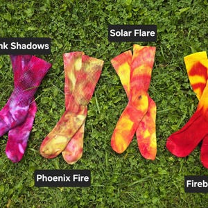 Peut inclure: Quatre paires de chaussettes montantes tie-dye avec des motifs de couleurs distincts &eacute;tiquet&eacute;s Pink Shadows en magenta et violet, Phoenix Fire en orange et jaune, Solar Flare en jaune et orange, et Fireball en rouge vif et jaune.