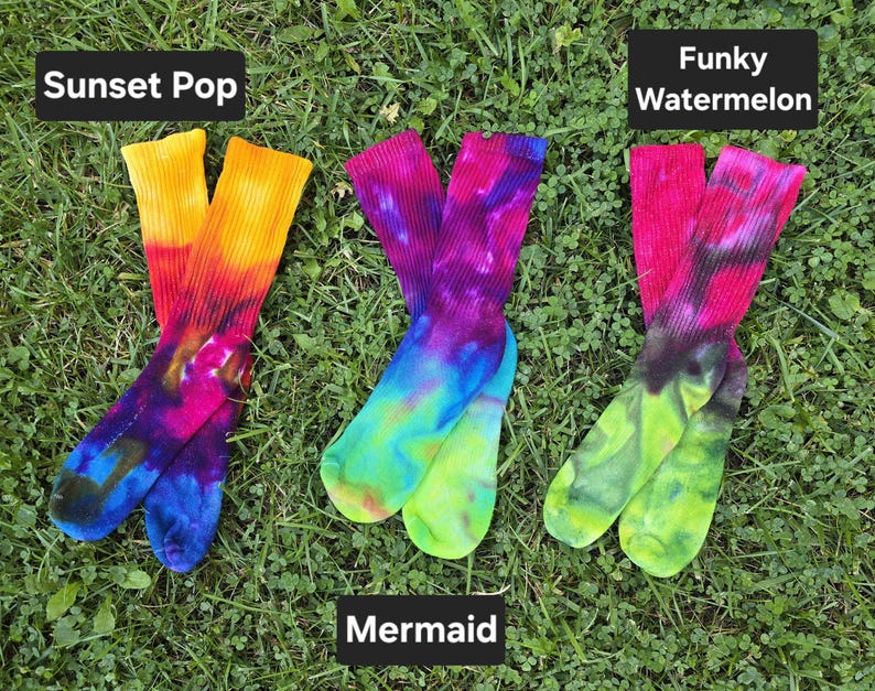 Peut inclure: Trois paires de chaussettes tie-dye. La premi&egrave;re paire, &eacute;tiquet&eacute;e Sunset Pop, pr&eacute;sente du jaune, de l'orange, du rose et du bleu. La deuxi&egrave;me, Mermaid, montre du violet, du bleu et du vert. La troisi&egrave;me, Funky Watermelon, affiche du rose, du noir et du vert lime.