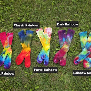 Peut inclure: Cinq paires de chaussettes montantes tie-dye dispos&eacute;es en rang&eacute;e. Les &eacute;tiquettes identifient les motifs de couleurs comme Bright Rainbow, Classic Rainbow, Pastel Rainbow, Dark Rainbow et Rainbow Swirl. Chaque paire pr&eacute;sente un m&eacute;lange unique.