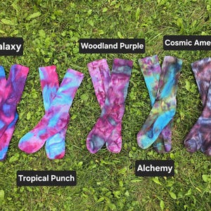 Peut inclure: Cinq paires de chaussettes montantes tie-dye dispos&eacute;es en rang&eacute;e. Les paires sont &eacute;tiquet&eacute;es Galaxy, Tropical Punch, Woodland Purple, Alchemy et Cosmic Amethyst. Chaque paire pr&eacute;sente un m&eacute;lange unique de couleurs vives, dont rose, bleu, violet et vert.