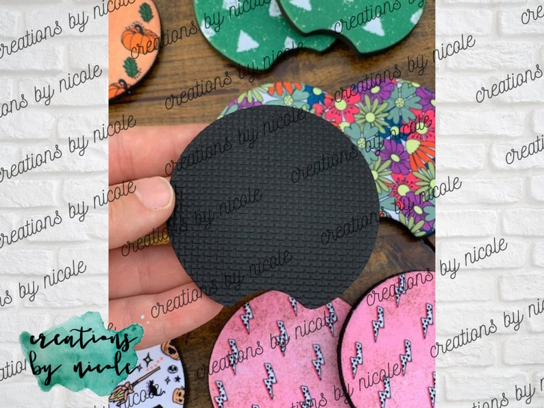 May include: A set of six round coasters with various designs. The coasters are made of a cork-like material with a black rubber backing. The designs include a floral pattern, a lightning bolt pattern, a pumpkin pattern, a witch pattern, and a Christmas tree pattern.