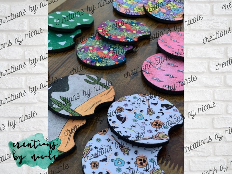 May include: A collection of colorful and patterned beverage coasters. The coasters are made of a soft, absorbent material and feature various designs, including cacti, flowers, and Halloween-themed patterns. The coasters are all round and have a slightly raised edge.