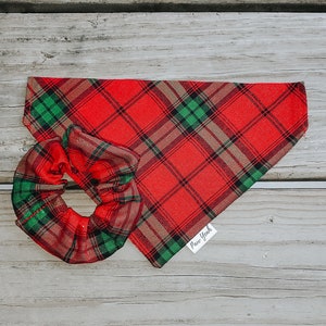 May include: Red and green plaid dog bandana with a matching scrunchie. The bandana has a white tag that says "Paw York".