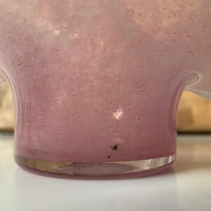 May include: A pink glass vase with a textured surface and a rounded base.
