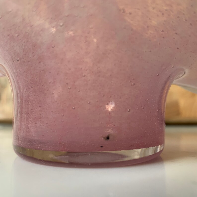 May include: A pink glass vase with a textured surface and a rounded base.