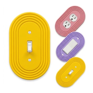 May include: A collection of colorful electrical outlet and light switch covers. The covers are in shades of yellow, pink, and purple. The light switch covers have a white switch. The outlet cover has two electrical outlets.