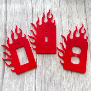May include: Three red plastic light switch covers shaped like flames. Each cover has a different switch plate cutout.