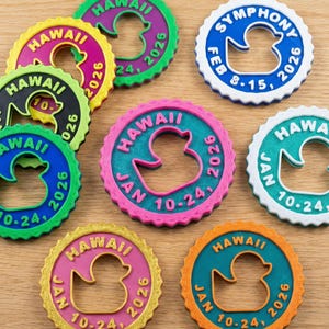 May include: A collection of circular, scalloped-edge plastic tags featuring a central duck-shaped cutout. Each tag displays text including locations like Hawaii or Symphony, and dates such as Jan 10-24, 2026, or Feb 8-15, 2026, in various color combinations.