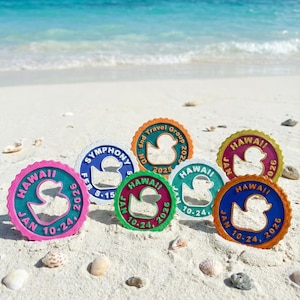 May include: Seven circular plastic tags with scalloped edges, each featuring a central duck cutout. The tags display various colors including pink, blue, orange, green, and yellow, with printed text such as HAWAII, SYMPHONY, and dates like JAN 10-24, 2026.