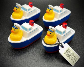 May include: Four toy boats with a yellow rubber ducky wearing a captain's hat. The boats are white with blue hulls and red smokestacks. One boat has a tag that says "Grab Yours Today".