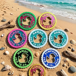 May include: Seven circular plastic tags with scalloped edges, each featuring a central rubber duck cutout. Six tags display "HAWAII JAN 10-24, 2026" in various color combinations, while one blue tag displays "SYMPHONY FEB 8-15, 2026" in white lettering.