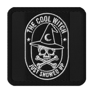Op de afbeelding: Zwart geborduurde patch met een schedel met een heksenhoed en een halve maan. De tekst "THE COOL WITCH" staat boven de hoed en "JUST SHOWED UP" eronder. De patch is omrand door een zwarte rechthoek.
