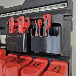 May include: A black plastic tool organizer with multiple slots for holding tools. The organizer is mounted on a black tool box. The organizer has the text "Folding Hex Key" printed on it. The tool box has red and black tool containers labeled "Driver Bits", "Drill Bits", and "Drivers".