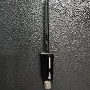 May include: A black wireless adapter with a black antenna and a silver connector. The adapter has the text "Snoff" printed on it.