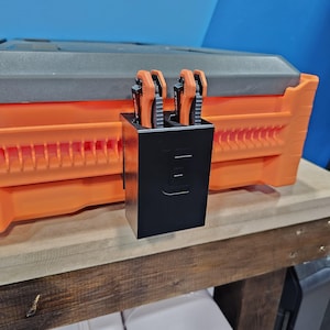 May include: A black plastic knife holder with two orange pocket knives inside. The holder is attached to an orange toolbox.