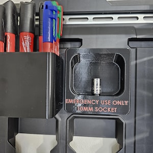 May include: A black tool organizer with a compartment for a 10mm socket. The compartment has a label that reads "Emergency Use Only 10mm Socket". There are also several black and red markers in a holder on the left side of the organizer.