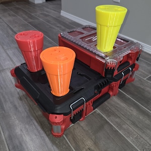 May include: A red and black tool box with three orange and yellow cups on top. The cups are stacked on top of each other.
