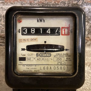 May include: Black electric meter with a white face and a digital display showing 3814.1 kWh. The meter is labeled "kWh" and "Z/75/C 12KW". It also has the text "Type CL27", "Landis & Gyr", "Single Phase Watt-Hour Meter", "240 V 40 A 50~", "250 REVS per kWh", "The Property of: The London Electricity Board", and "L68A 05801".