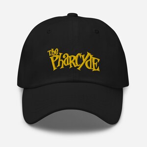 Può includere: Cappellino da baseball nero con un logo ricamato in oro che dice "The Pharcyde".