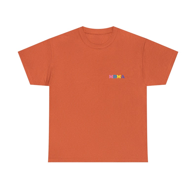 Op de afbeelding: Een oranje T-shirt met het woord "MOMA" geborduurd op de voorkant in kleurrijke letters.