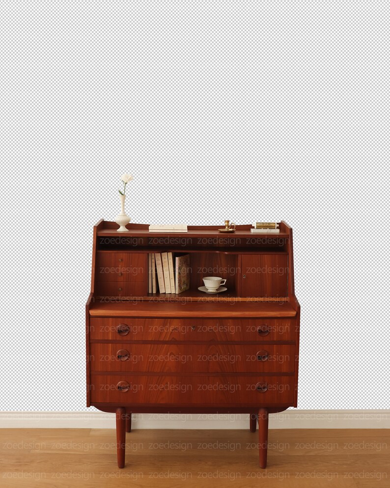 May include: A vintage wooden desk with a drop-down front and three drawers. The desk has a small shelf above the drop-down front and a small white vase with a single white flower on the shelf. There is a small white teacup and saucer on the desk.