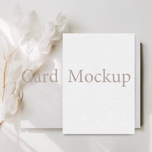 May include: A white card mockup with the text "Card Mockup" on a white background with a white branch with dried leaves.
