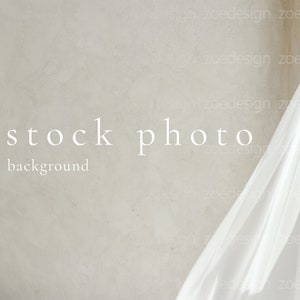 Pu&ograve; includere: Un tessuto bianco drappeggiato su una parete testurizzata grigio chiaro. Il testo "stock photo background" &egrave; stampato in bianco sul muro.