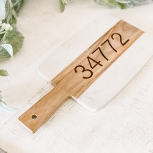 May include: A white and brown rectangular serving board with a wooden handle. The number 34772 is engraved on the board.