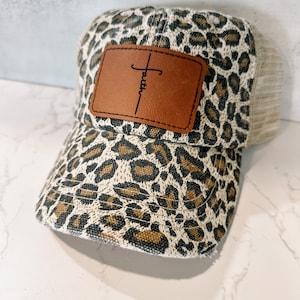 Faith Cross animal print vintage distressed ponytail or bun ladies leopard cheetah print snap back baseball trucker hat with leather patch