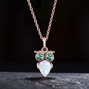 Op de afbeelding: Een ketting van roségoud met een uil hanger. De uil heeft groene ogen en een wit opaal lichaam.