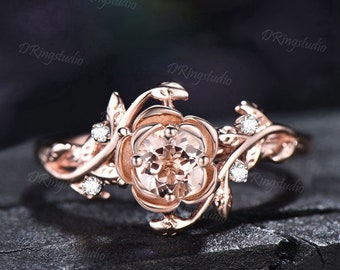 May include: Rose gold engagement ring with a morganite center stone and diamond accents. The ring features a delicate floral design with leaves and vines.