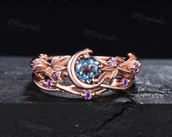 May include: A rose gold ring with a crescent moon design and a blue gemstone. The ring is adorned with small pink gemstones and intricate leaf details.
