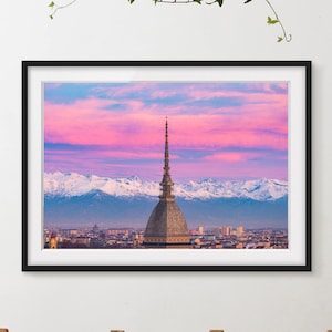 Puede incluir: Impresión enmarcada de un paisaje urbano con una estructura abovedada prominente con una aguja, sobre un vibrante cielo rosa y azul al atardecer. Se ven montañas cubiertas de nieve en el fondo.