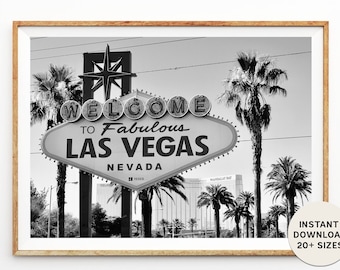 May include: Black and white photograph of the iconic "Welcome to Fabulous Las Vegas" sign with palm trees in the foreground and a building in the background.
