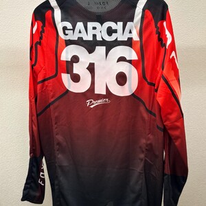 K&ouml;nnte beinhalten: Langarm-Trikot in Rot, Schwarz und Wei&szlig; mit "Garcia 316 Premier" auf der R&uuml;ckseite.