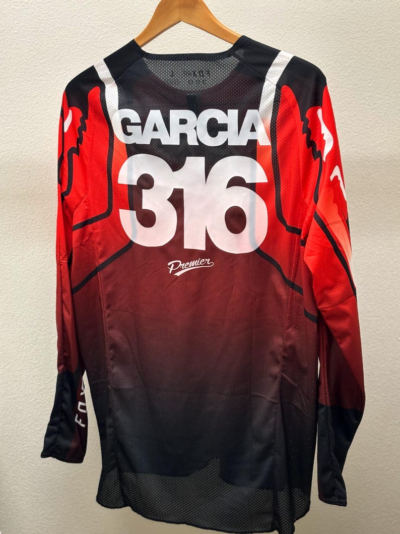 K&ouml;nnte beinhalten: Langarm-Trikot in Rot, Schwarz und Wei&szlig; mit "Garcia 316 Premier" auf der R&uuml;ckseite.
