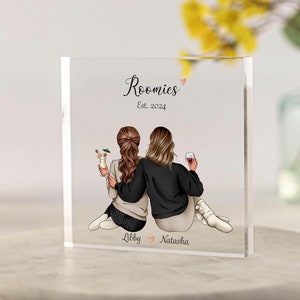 May include: A clear acrylic block with a personalized illustration of two women holding drinks. The text "Roomies Est. 2024" is at the top of the block, and the names "Libby" and "Natasha" are at the bottom.