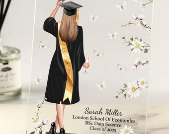 May include: A clear acrylic plaque with a black base featuring a digital illustration of a graduate in a black cap and gown holding a diploma. The graduate is wearing a gold sash with the word "Congrats" on it. The background is decorated with white flowers and butterflies. The text "Sarah Miller, London School of Economics, BSc Data Science, Class of 2025" is printed on the plaque.