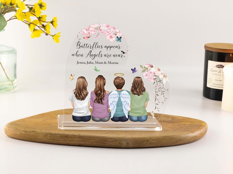 May include: A clear acrylic heart-shaped memorial plaque with a floral design and the text "Butterflies appear when Angels are near."  The plaque features four people, including one with angel wings, and the names "Jenna, Julia, Mum & Maxine".