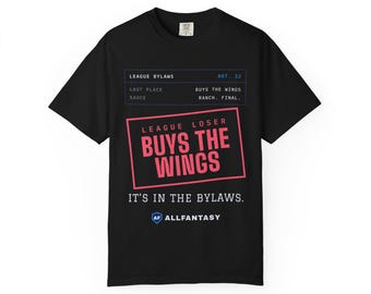 Puede incluir: Una camiseta negra de manga corta con texto en blanco y rosa que dice: LEAGUE BYLAWS ART. 12, LAST PLACE BUYS THE WINGS, SAUCE RANCH. FINAL. LEAGUE LOSER BUYS THE WINGS, IT'S IN THE BYLAWS. ALLFANTASY con un logotipo de escudo azul.