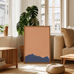 May include: A rectangular framed wall art print featuring a minimalist landscape illustration with dark blue mountain silhouettes against a solid terracotta orange sky filled with white stars and a small crescent moon in the lower right corner.