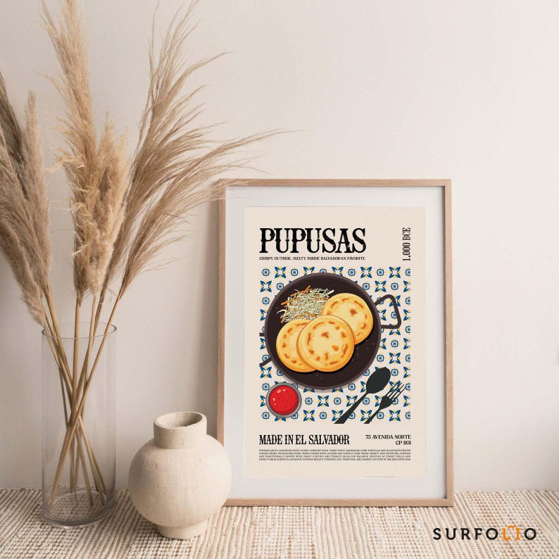 May include: A framed poster featuring the word "PUPUSAS" at the top. The poster includes an illustration of pupusas on a plate, a small bowl of sauce, and text that reads "MADE IN EL SALVADOR". The poster is in a wooden frame.
